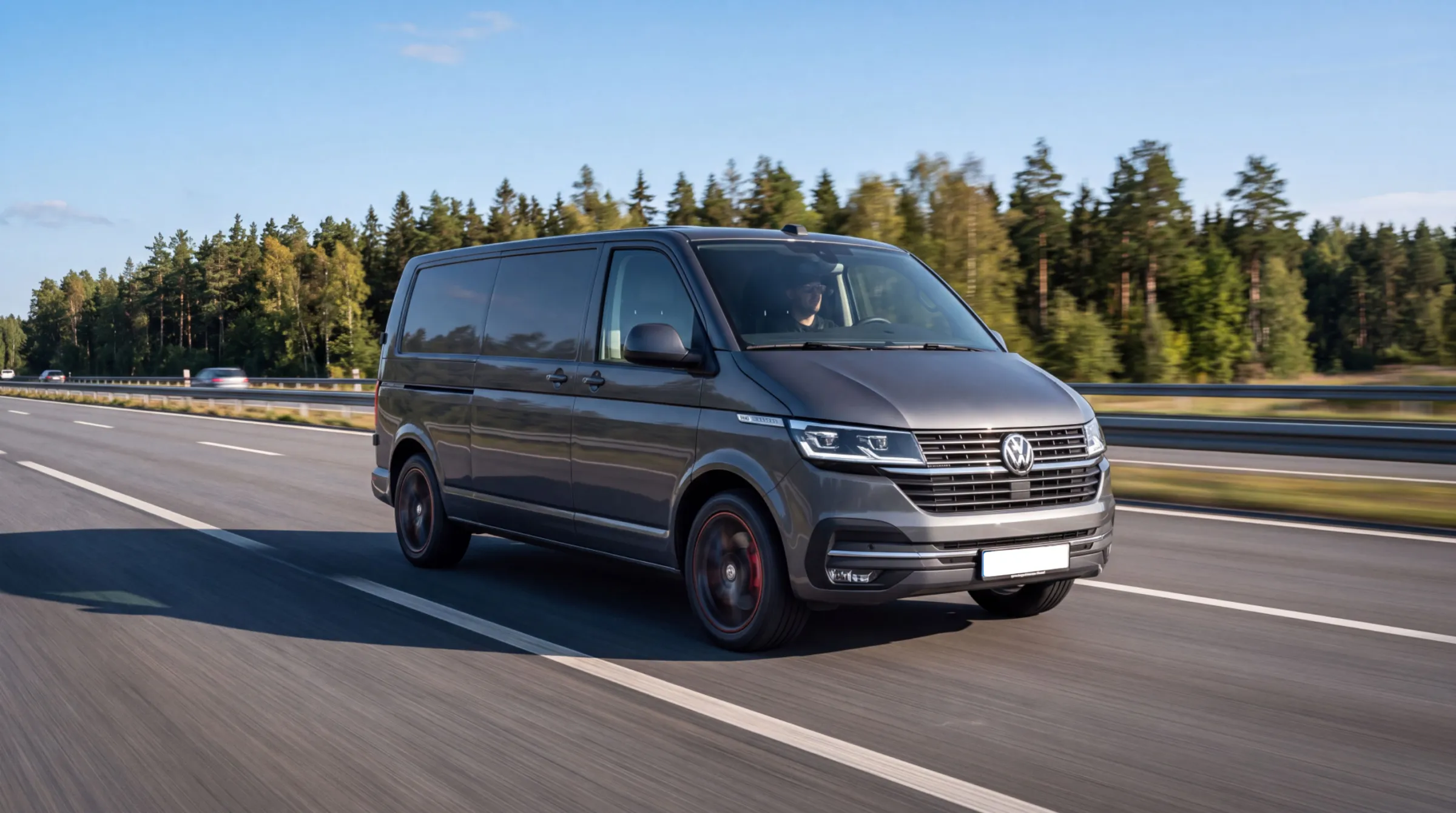 Szary Volkswagen Transporter przed halą, z otwartymi drzwiami bocznymi odsłaniającymi przestrzeń ładunkową